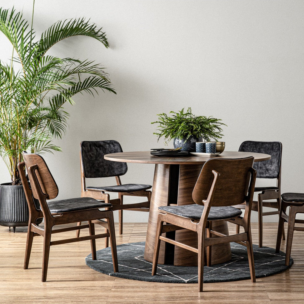 Dining room with wooden table and chairs, plants, and a neutral wall.