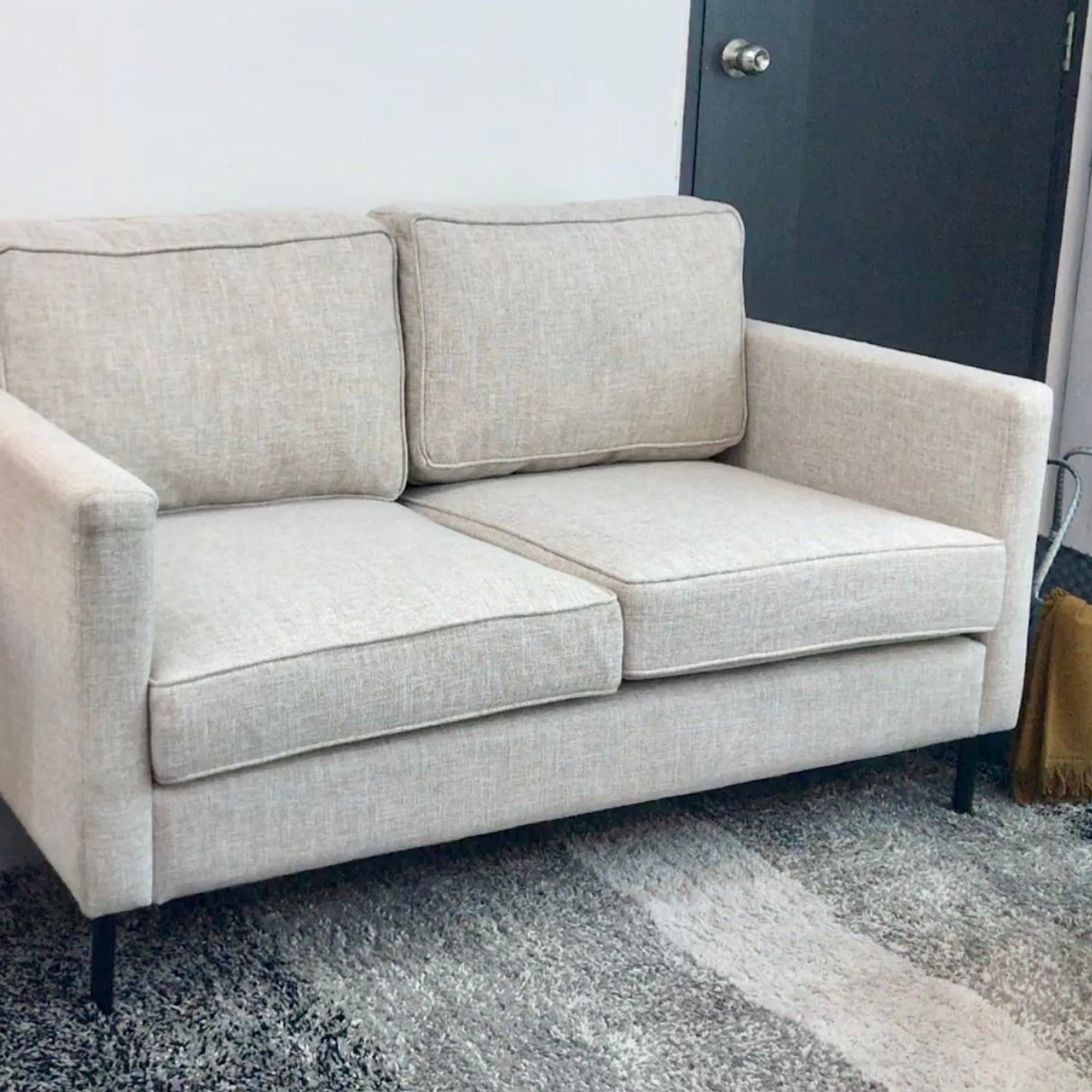 Light Brown sofa in a room with a rug and side table.