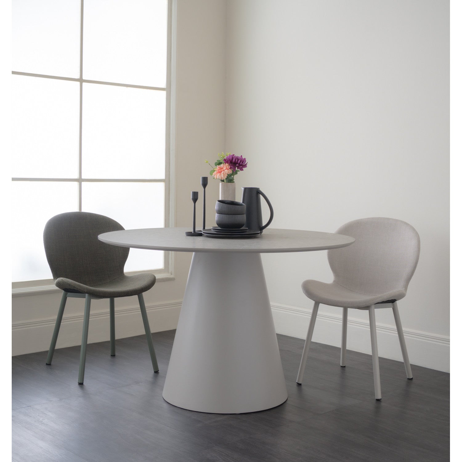 Modern dining set with a round table and two chairs in a minimalistic room.