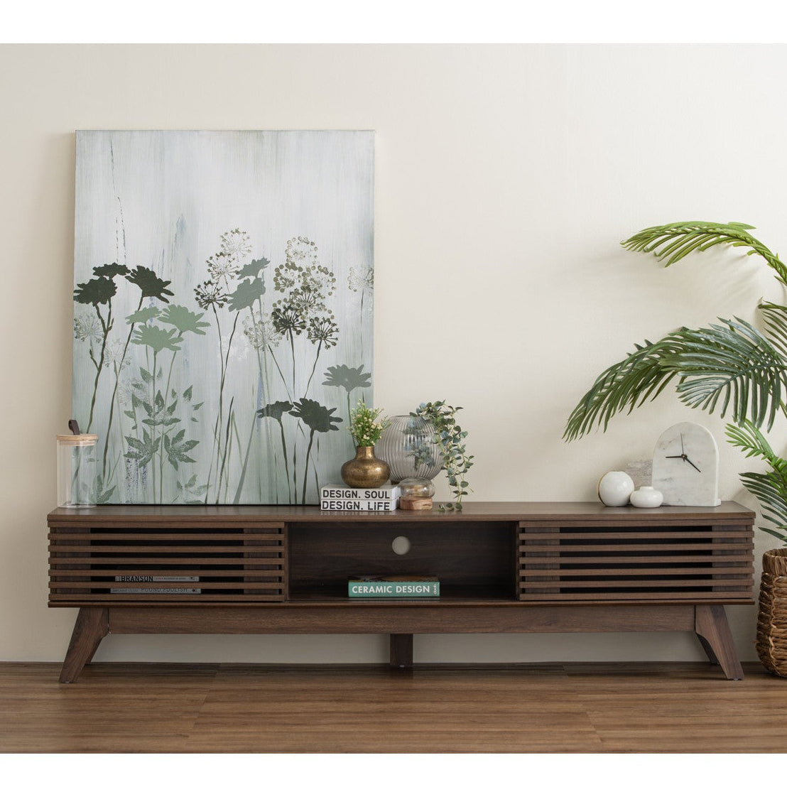 Modern living room with a wooden console table, decorative plants, and a large floral painting.