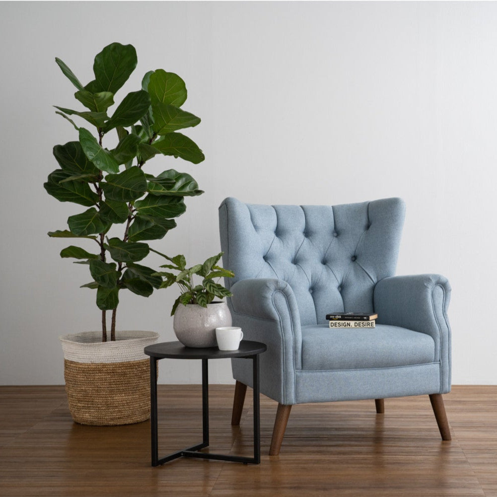 Blue armchair in a room with a plant and small table.