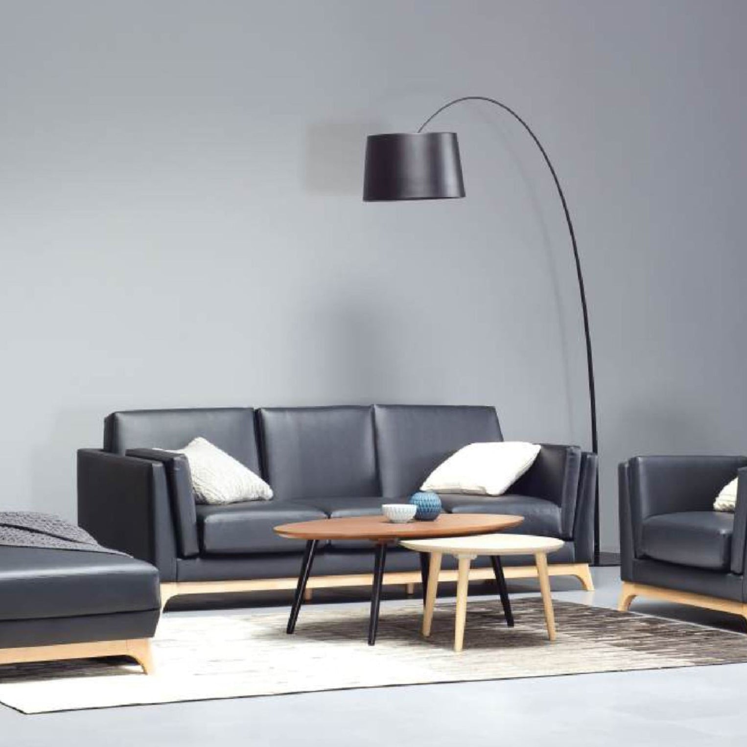 Modern living room with black leather furniture and a floor lamp.