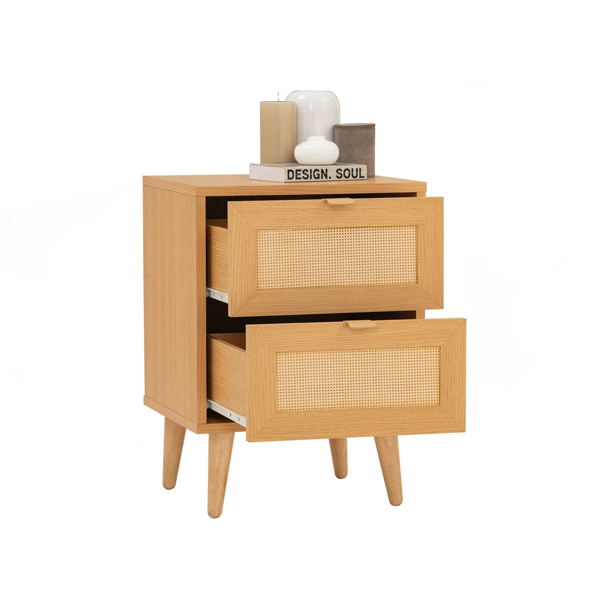 A mid-century modern two-drawer nightstand in light natural wood with woven cane panels on the drawer fronts and tapered legs, shown on a plain white background with decorative candles on top.