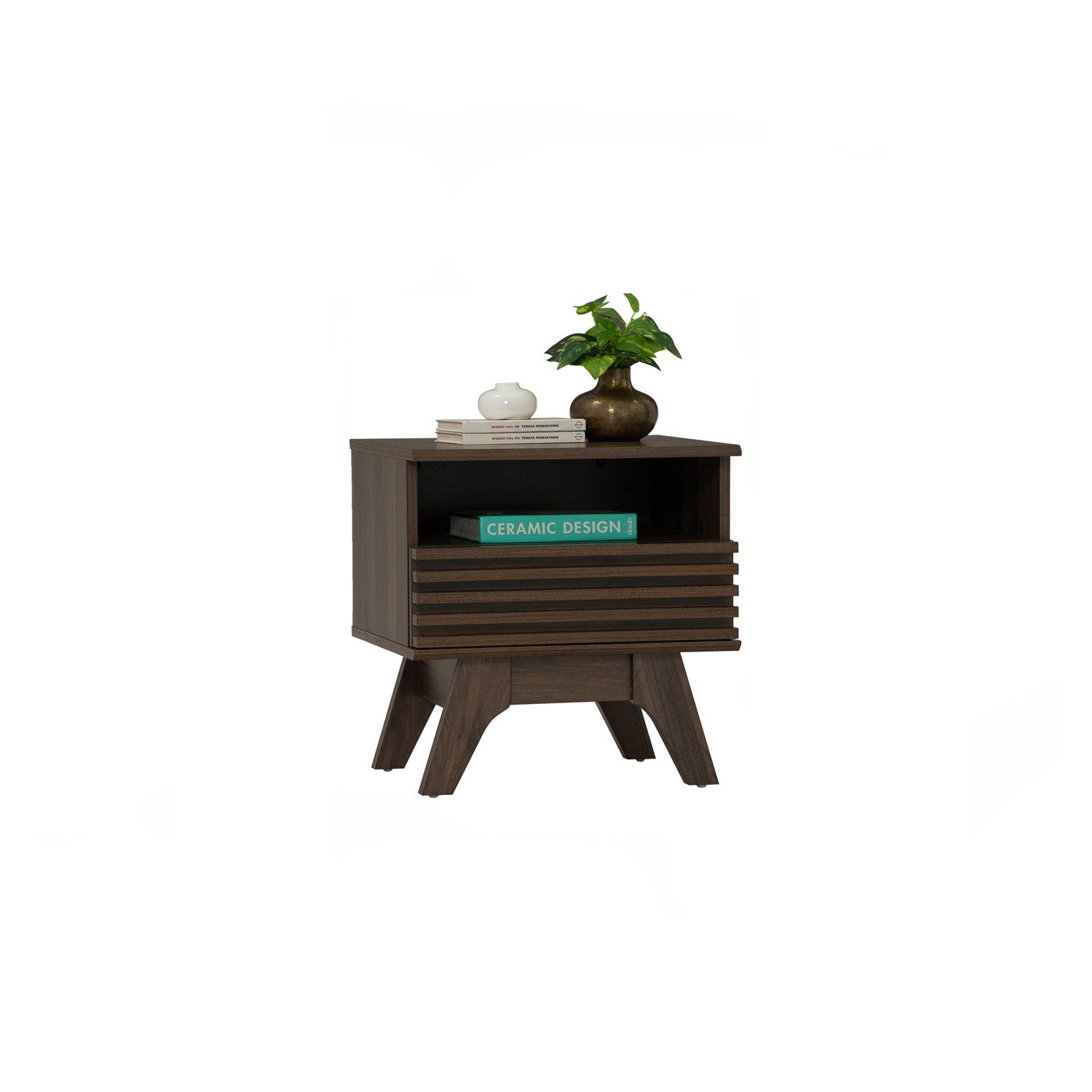 A dark brown wooden side table with a single open shelf and slatted front, styled with a small potted plant and books on top, set against a plain white background.