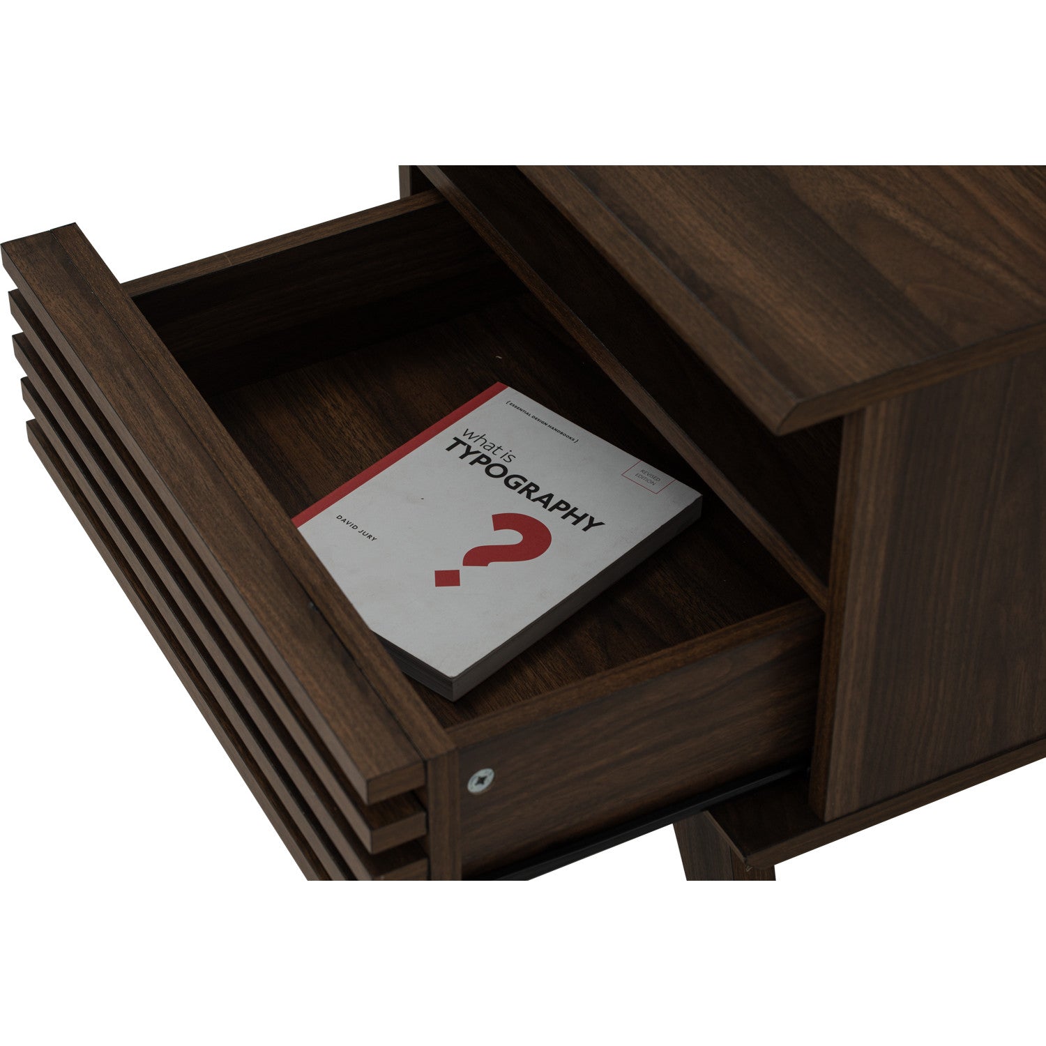 A close-up of a dark brown wooden drawer with its front pull handle partially visible, showing an open interior with a book inside on a white background.