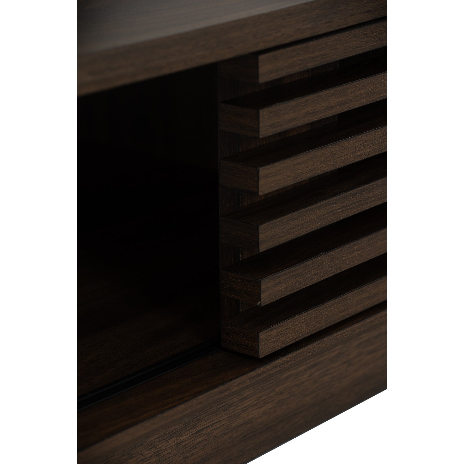 Close-up detail of a dark brown wooden cabinet or shelf with a slatted front panel and open storage compartment.