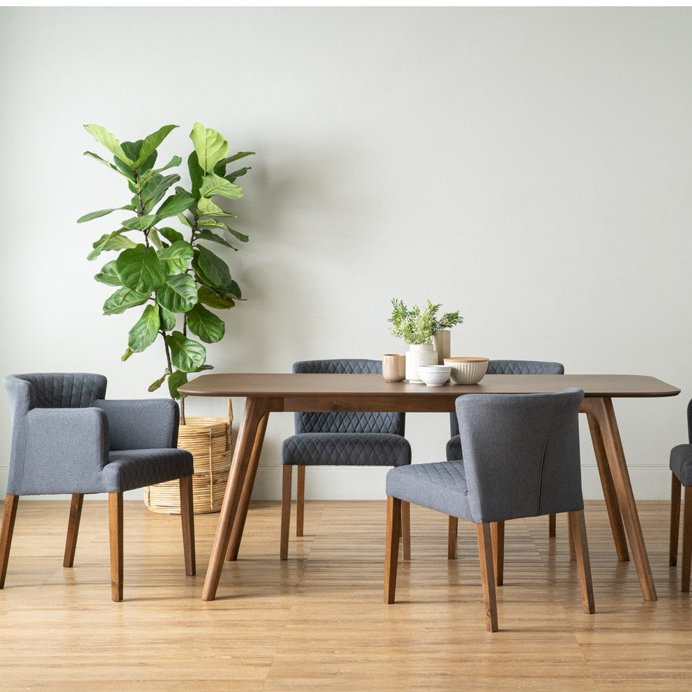 Dining room setup with a wooden table and gray chairs on a wooden floor.