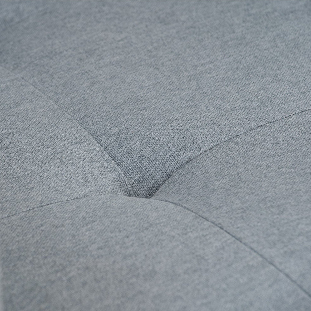 Close-up of a light gray tufted fabric surface with visible woven texture and stitched button details.