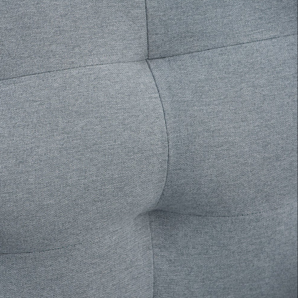 Close-up of a gray tufted fabric surface with stitched paneling and a soft, padded texture.