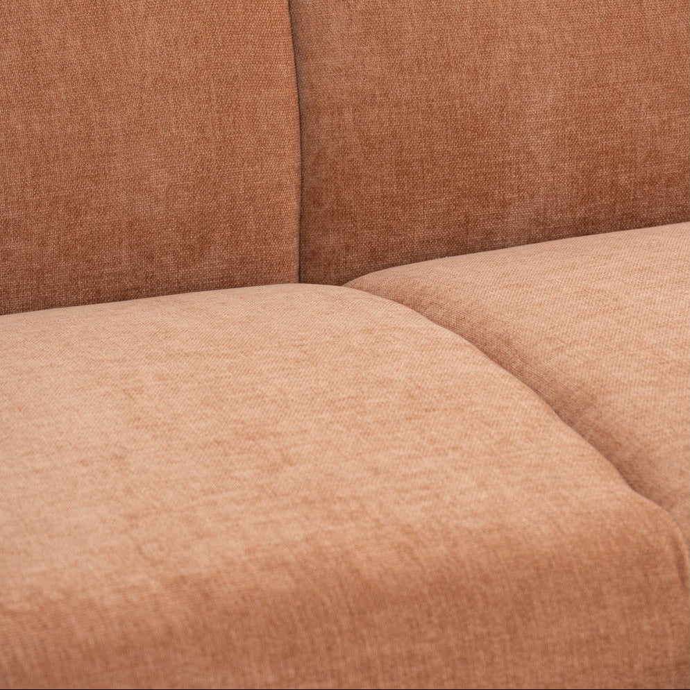 Close-up of a textured upholstered sofa or chair seat and back in a warm rust or terracotta tone, showing the fabric weave and seam lines.