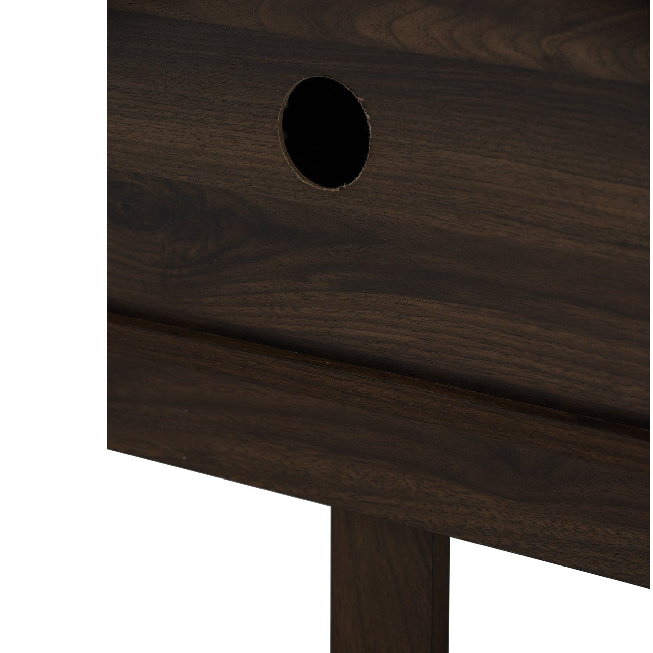 Close-up of a dark brown wood furniture piece showing a circular cutout and wood grain texture on a white background.