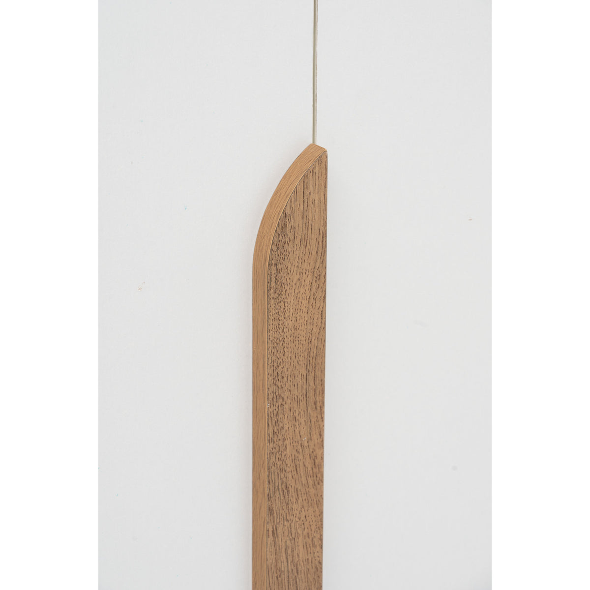Wooden spoon hanging against a white background
