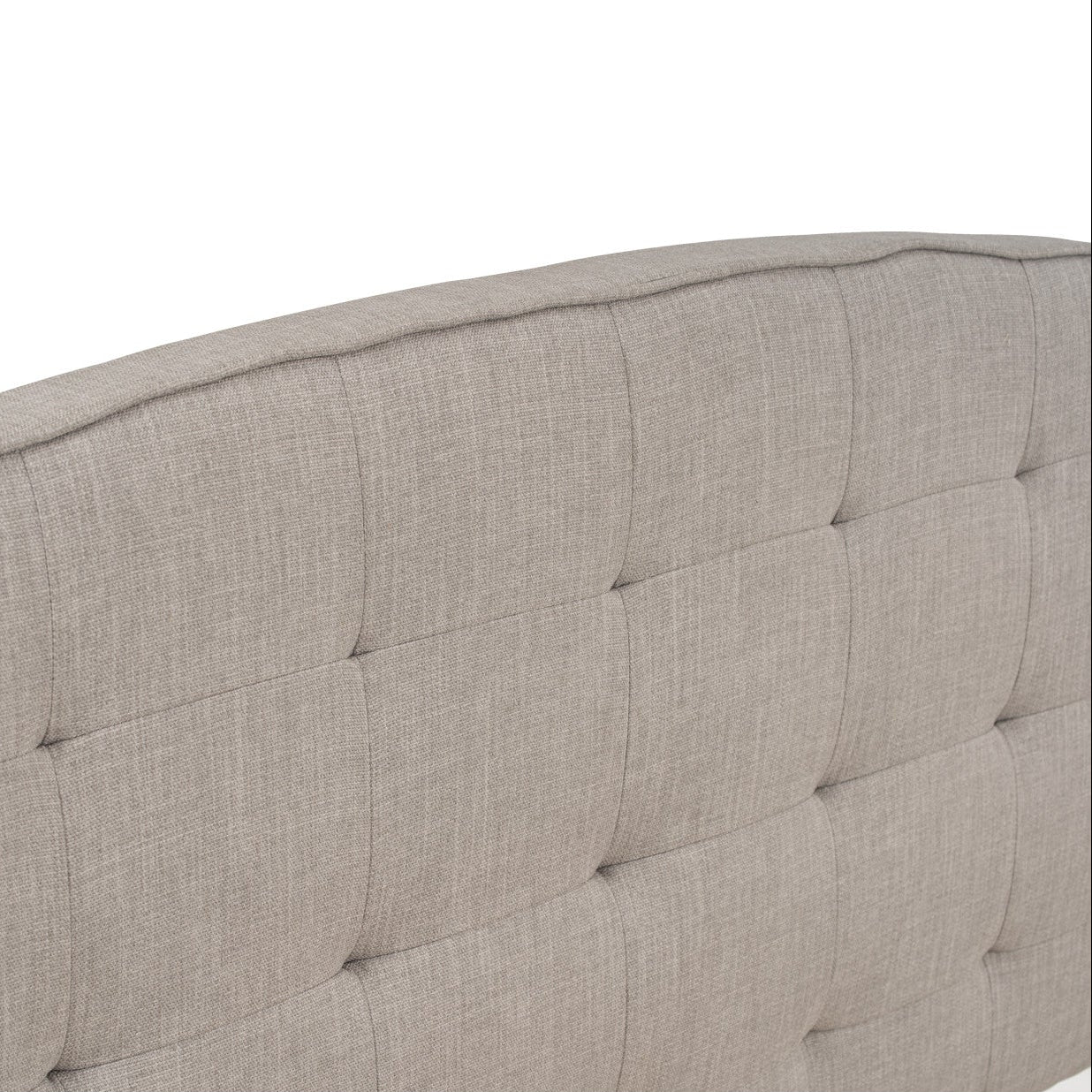 Close-up of a tufted headboard with a neutral color on a white background