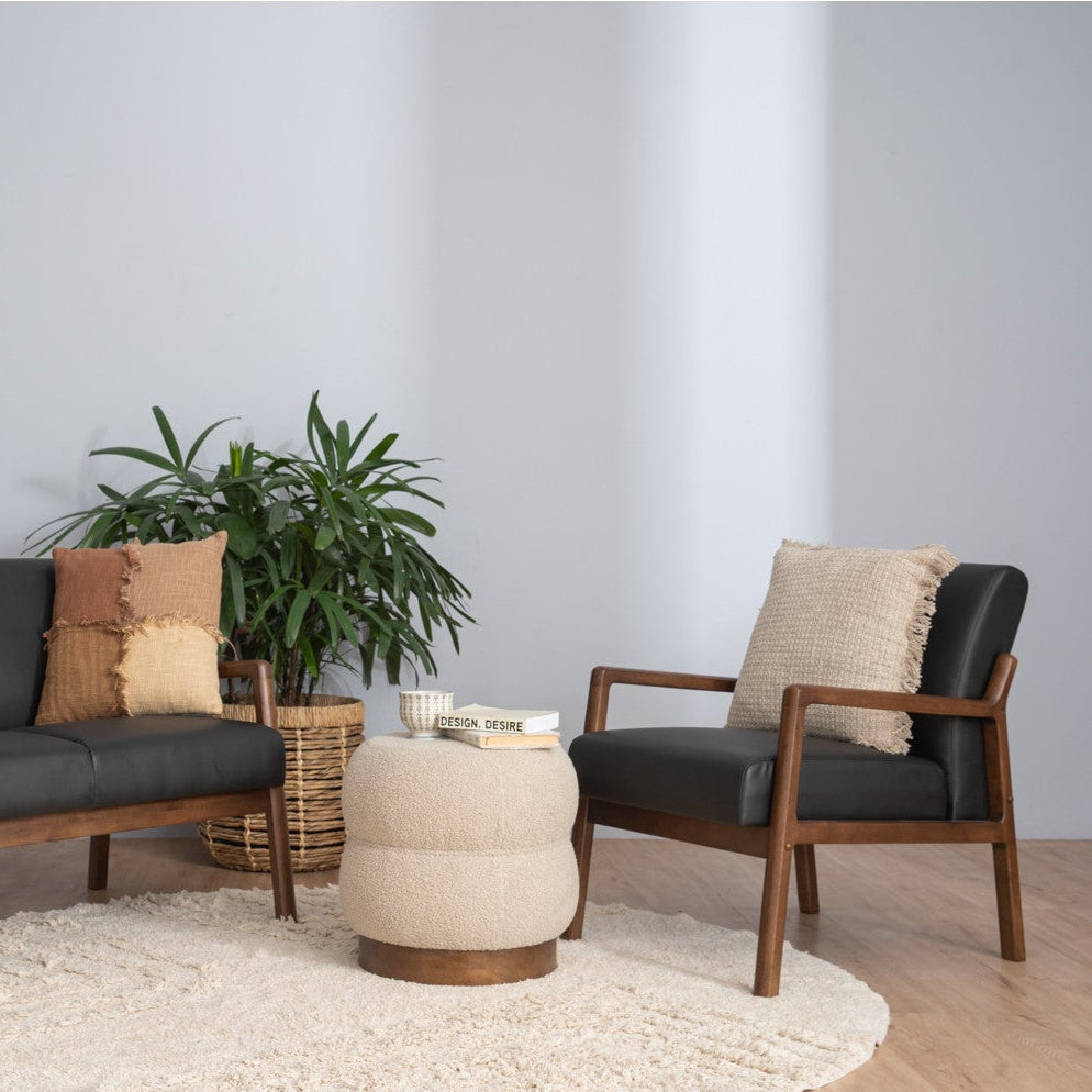 Modern living room with a sofa, armchair, ottoman, and plant on a light gray background