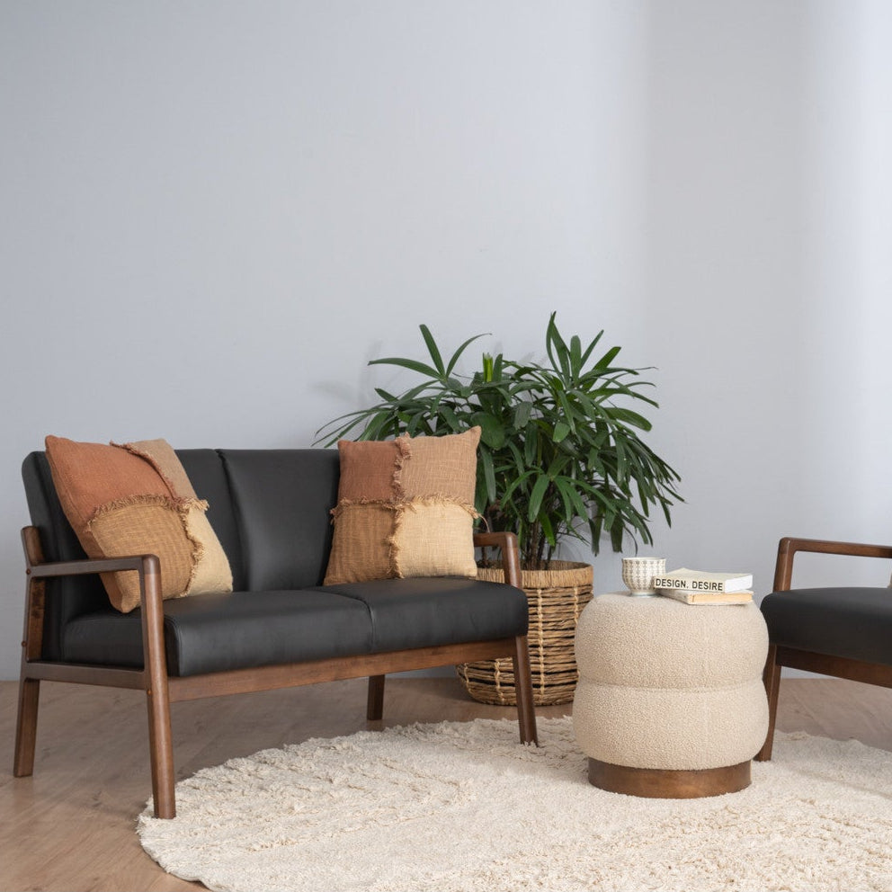 Modern living room with a sofa, armchair, ottoman, and plant on a light gray background