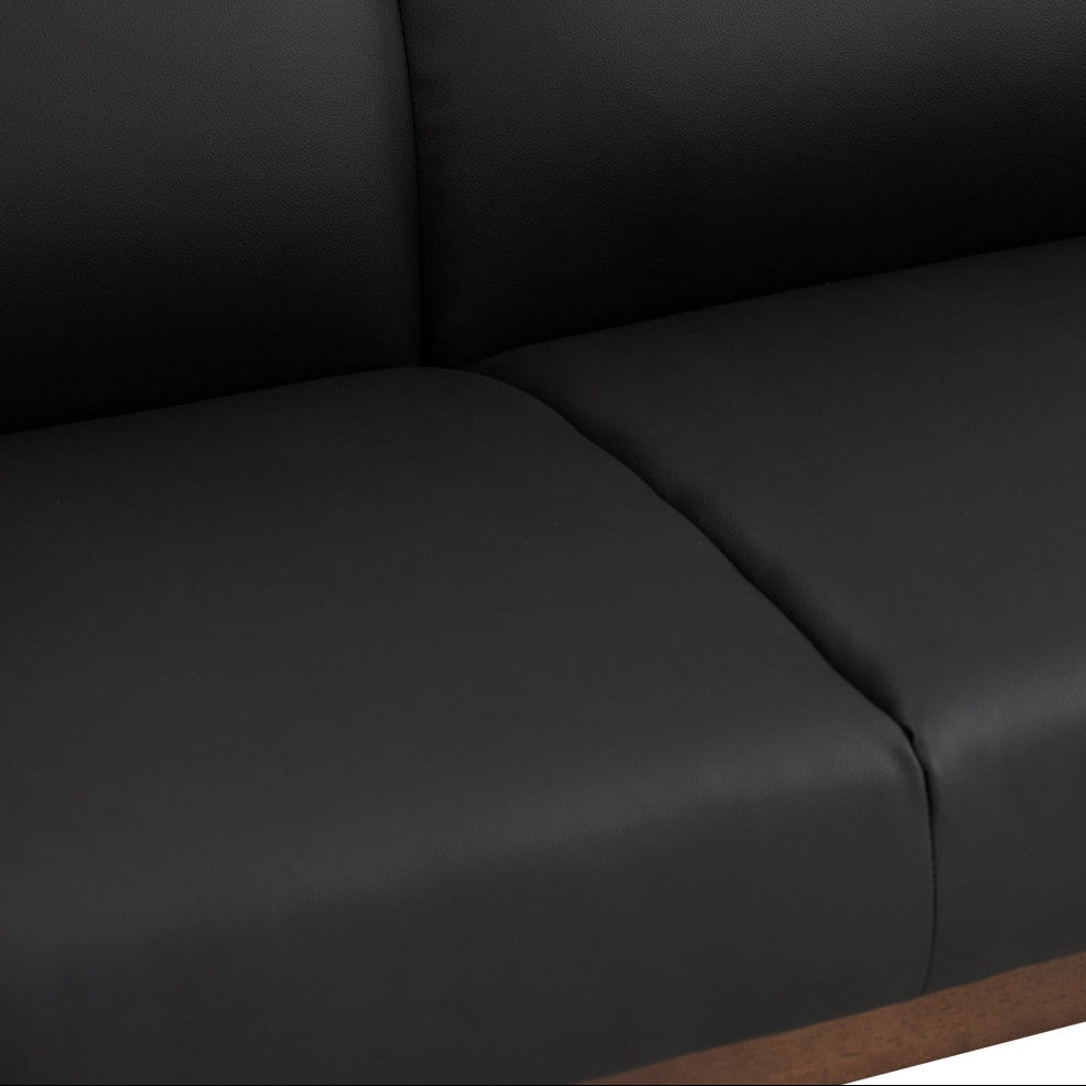 Close-up of a black upholstered seat and back cushion with visible seam lines and a small portion of a brown wooden base at the bottom.