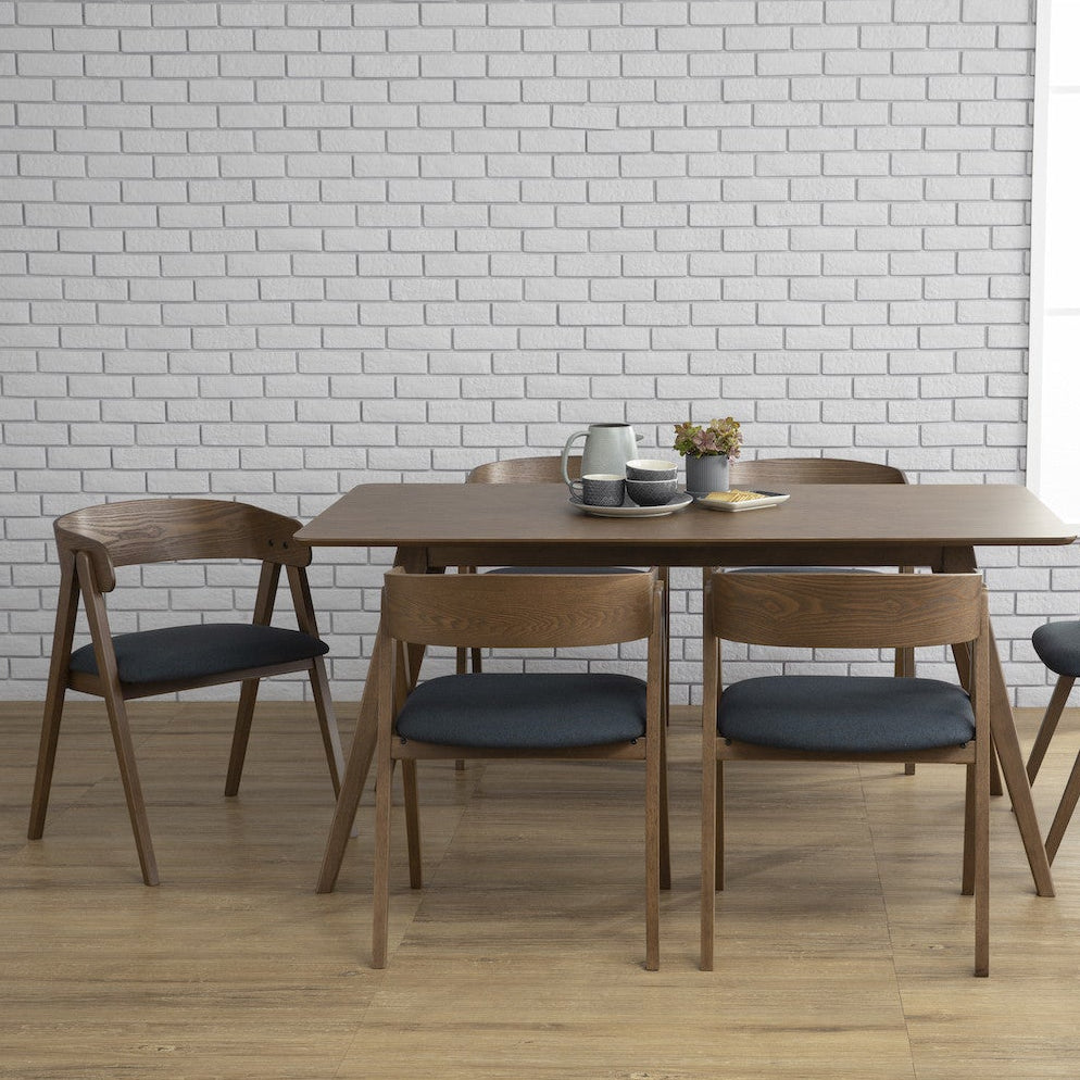 Dining table set with chairs against a white brick wall.