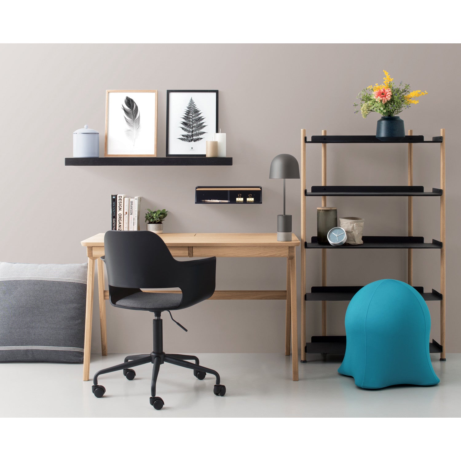 Modern home office with wooden desk, black chair, and decorative shelves.