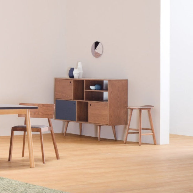 Modern dining room with wooden table, chairs, and shelves against a white wall.