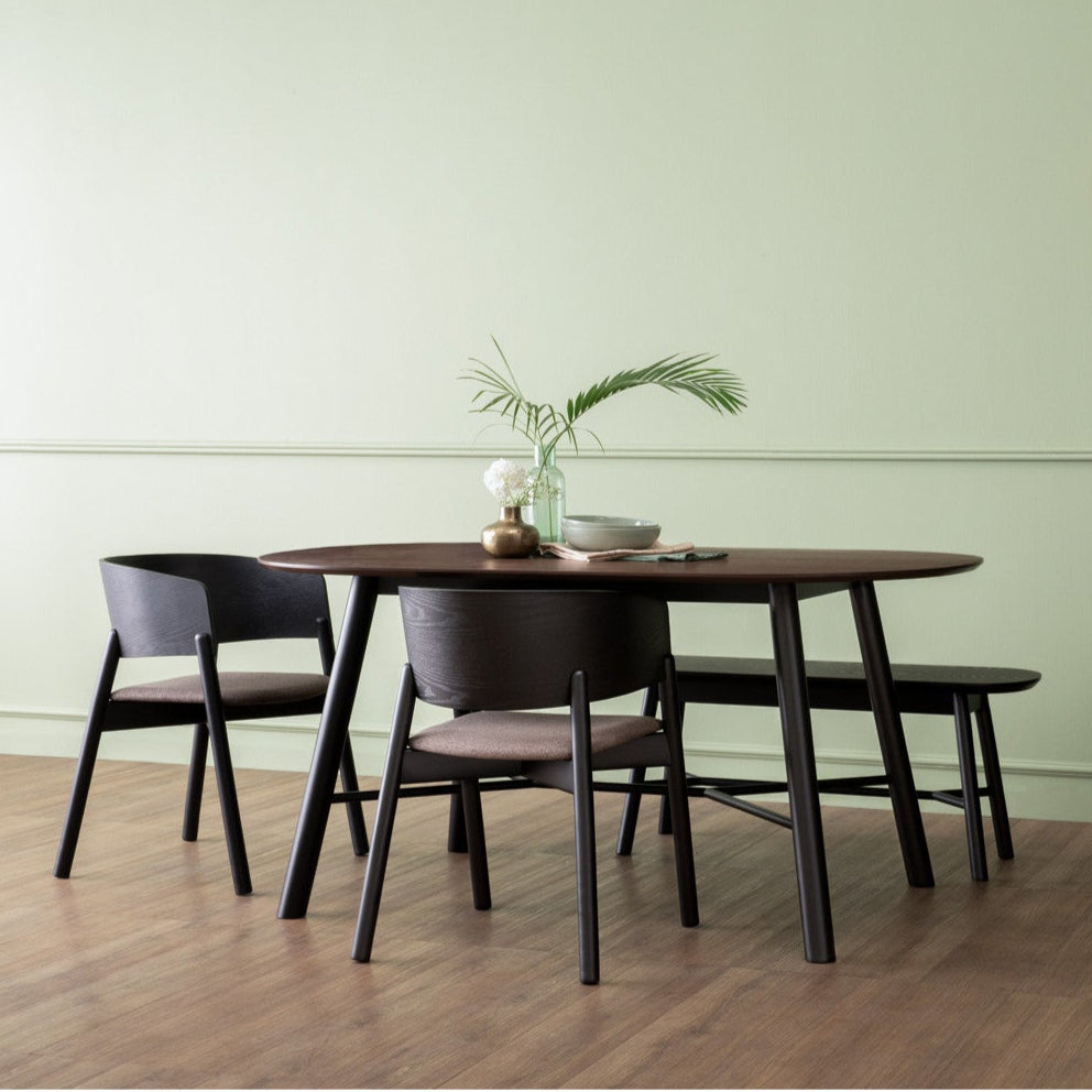 Dining area with a wooden table and chairs against a light green wall with a clock.
