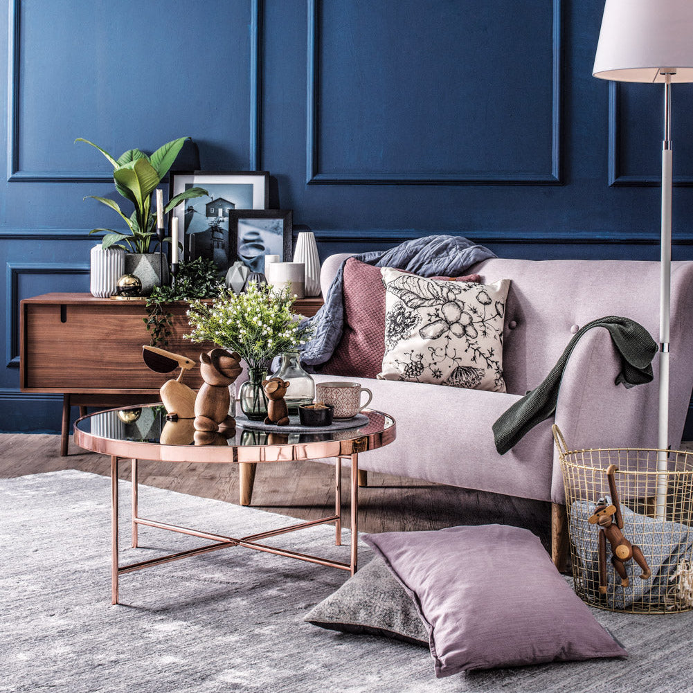 Living room with blue paneled walls, a pink sofa, and decorative items.