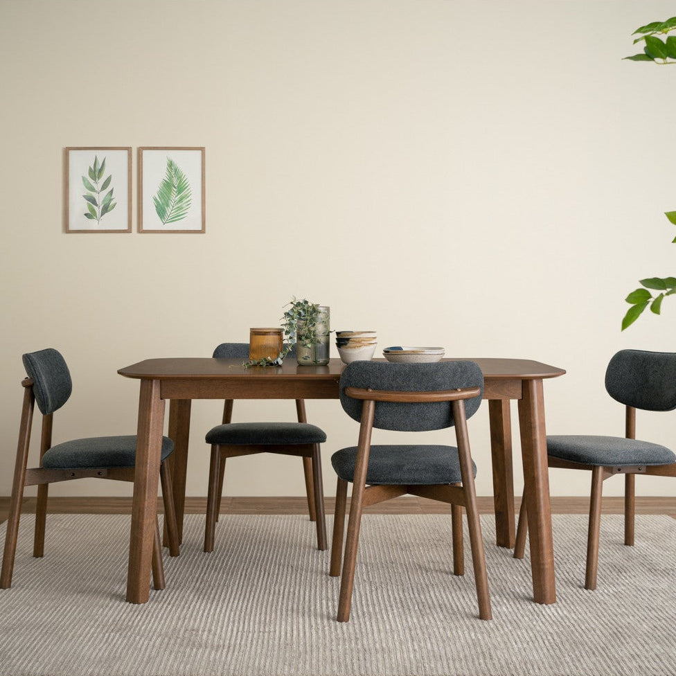 Dining room with wooden table and chairs on a rug, plants, and wall art.