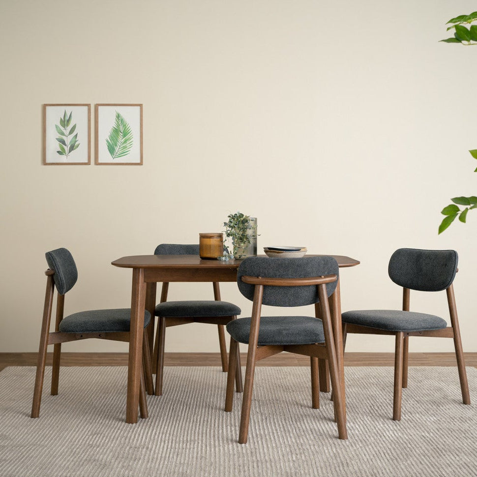 Dining room with wooden table and chairs on a rug, plants, and wall art.