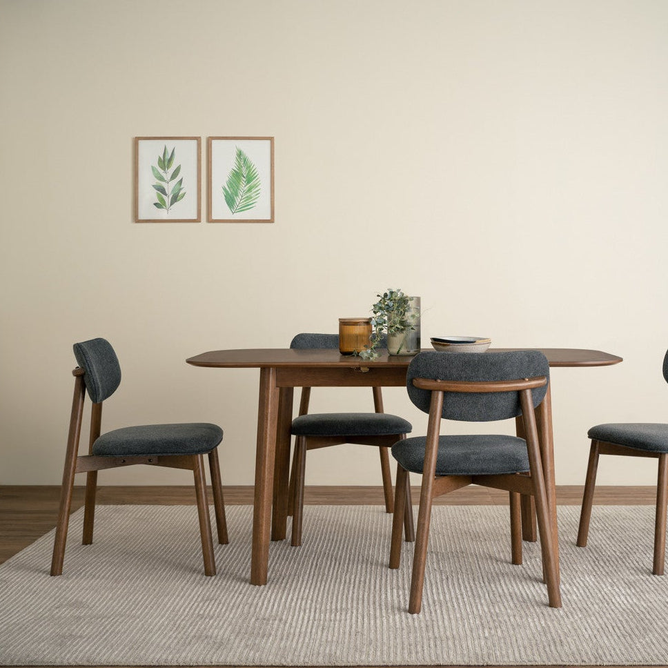 Dining room with wooden table and chairs against a beige wall with plant decorations.