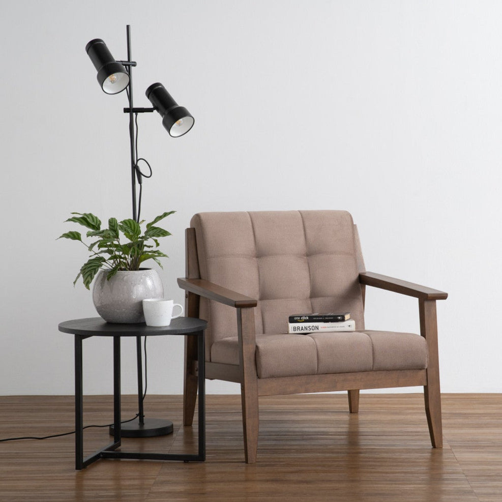Beige armchair with a side table and floor lamp in a minimalistic room.