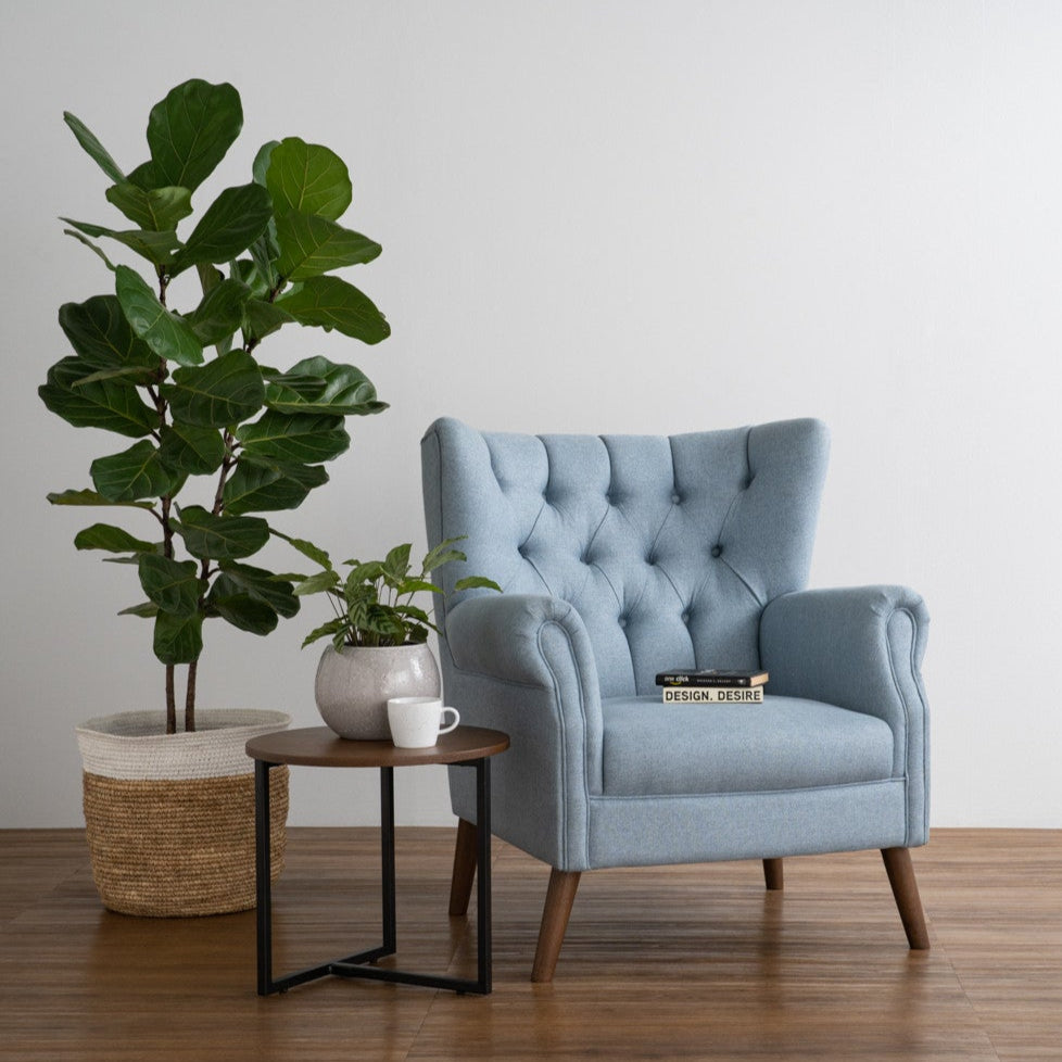 Blue armchair in a room with a plant and small table.
