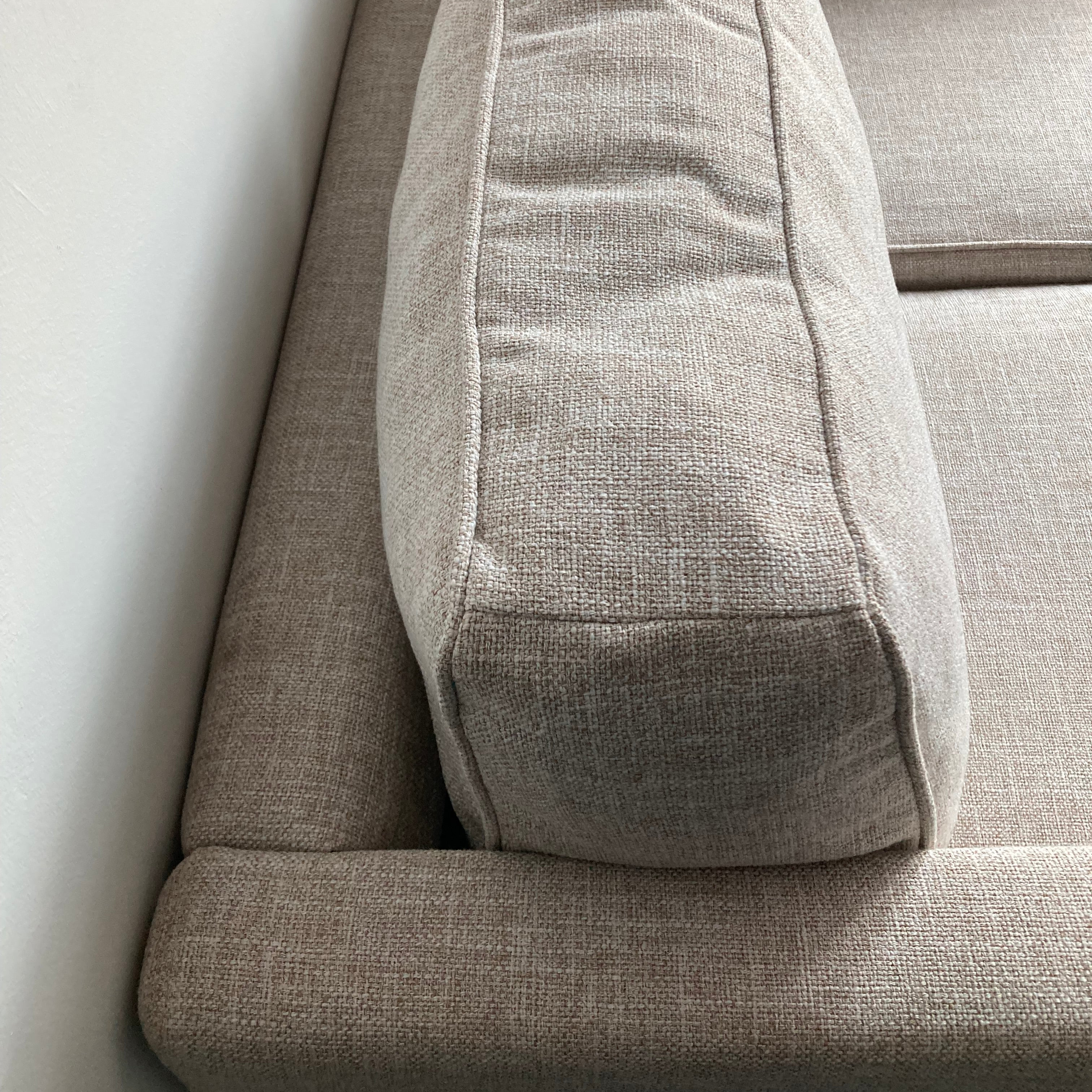 Close-up of a beige fabric sofa with a neutral background