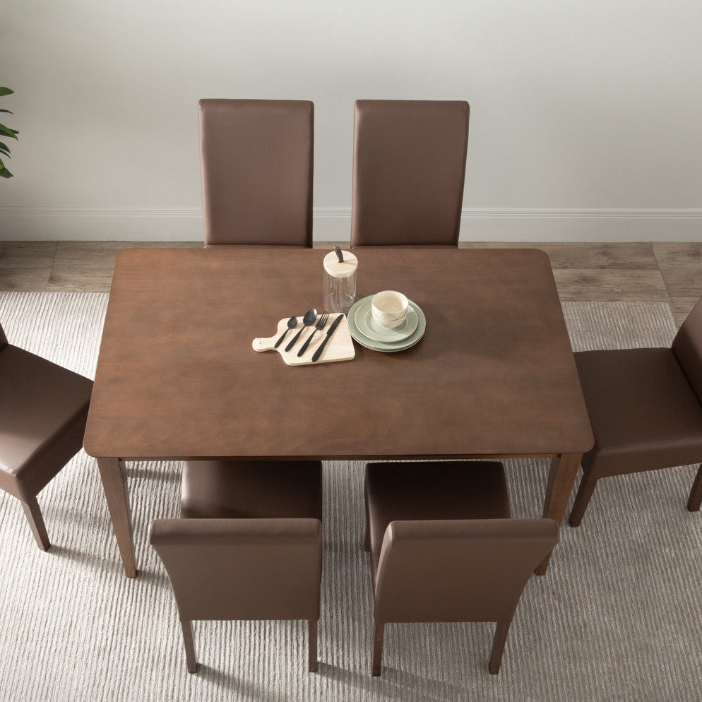 A 5-piece dining set featuring a rectangular brown wooden table and four matching brown upholstered chairs, arranged on a light gray rug in a bright room.