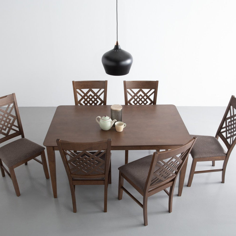Wooden dining table with six chairs on a gray floor and white wall background