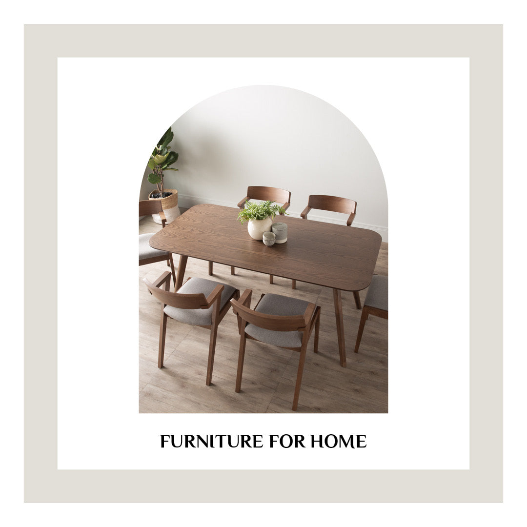A styled dining room scene showing a rectangular wooden table with four matching wooden chairs, set against a minimalist interior with a potted plant in the background. The image is framed with a wide beige border and the text 'FURNITURE FOR HOME' below.