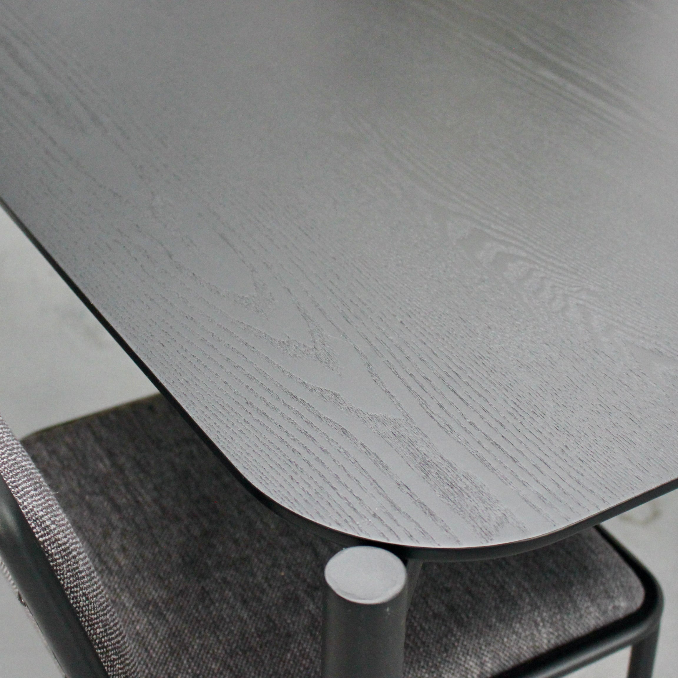 Blavk metal table with a chair underneath on a light gray floor.