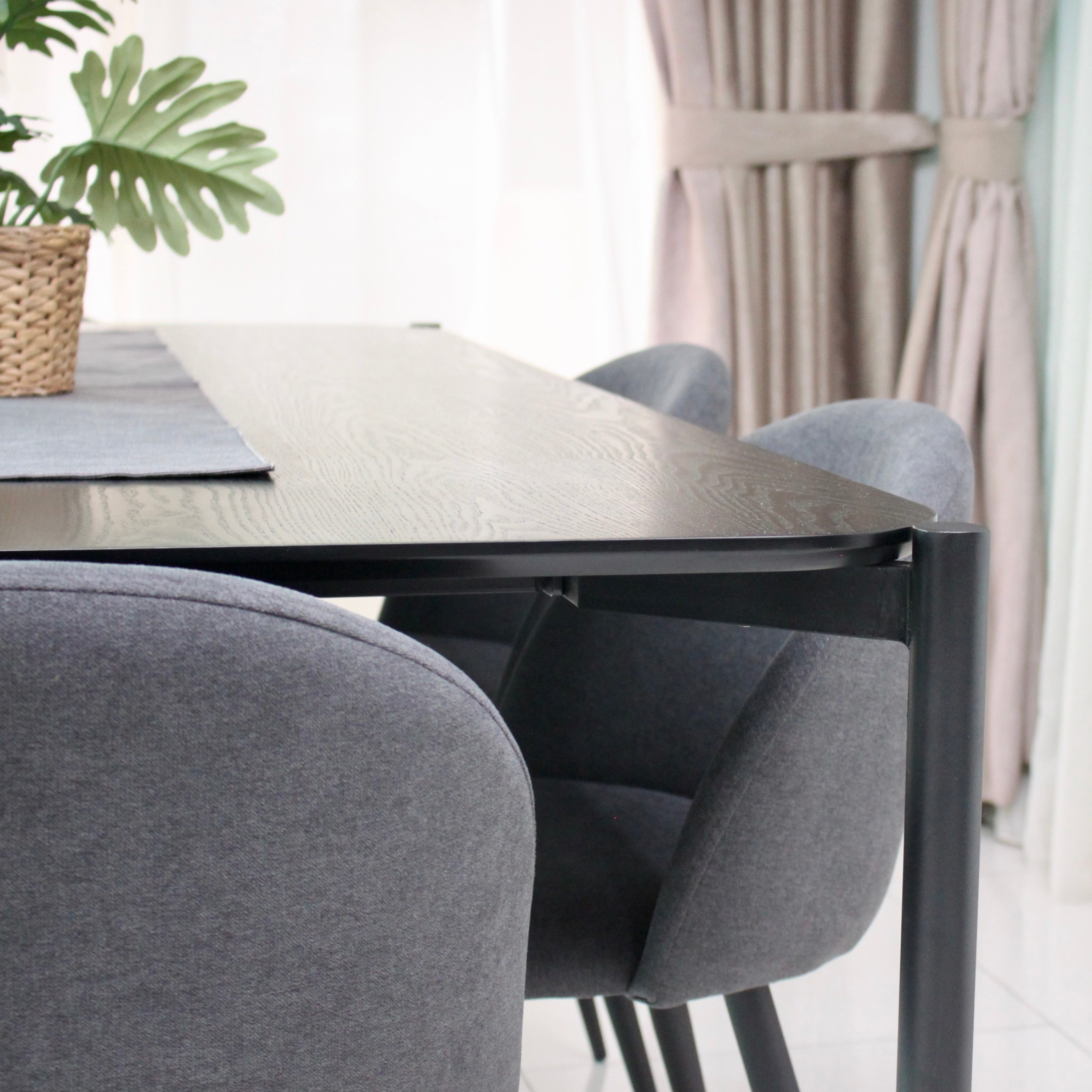 Dining table with gray chairs in a room with light-colored walls and a plant.