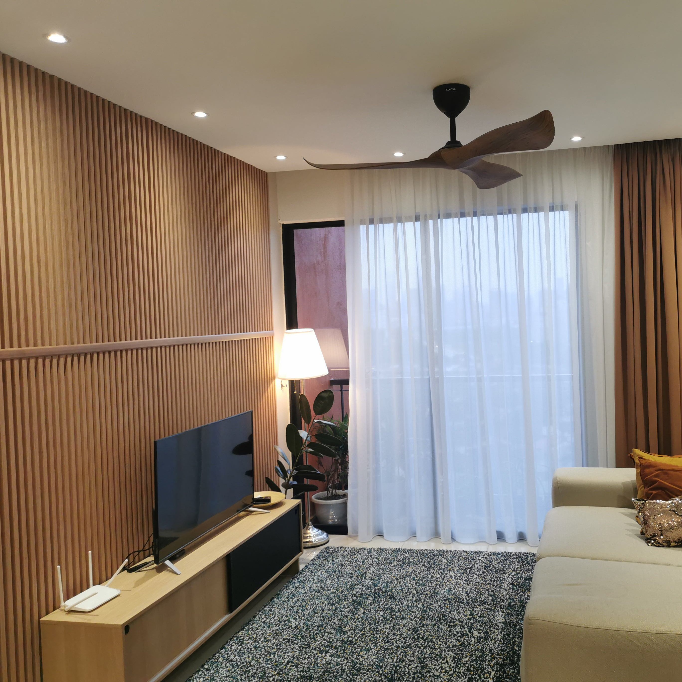 Modern living room with beige sofa, TV stand, and ceiling fan.