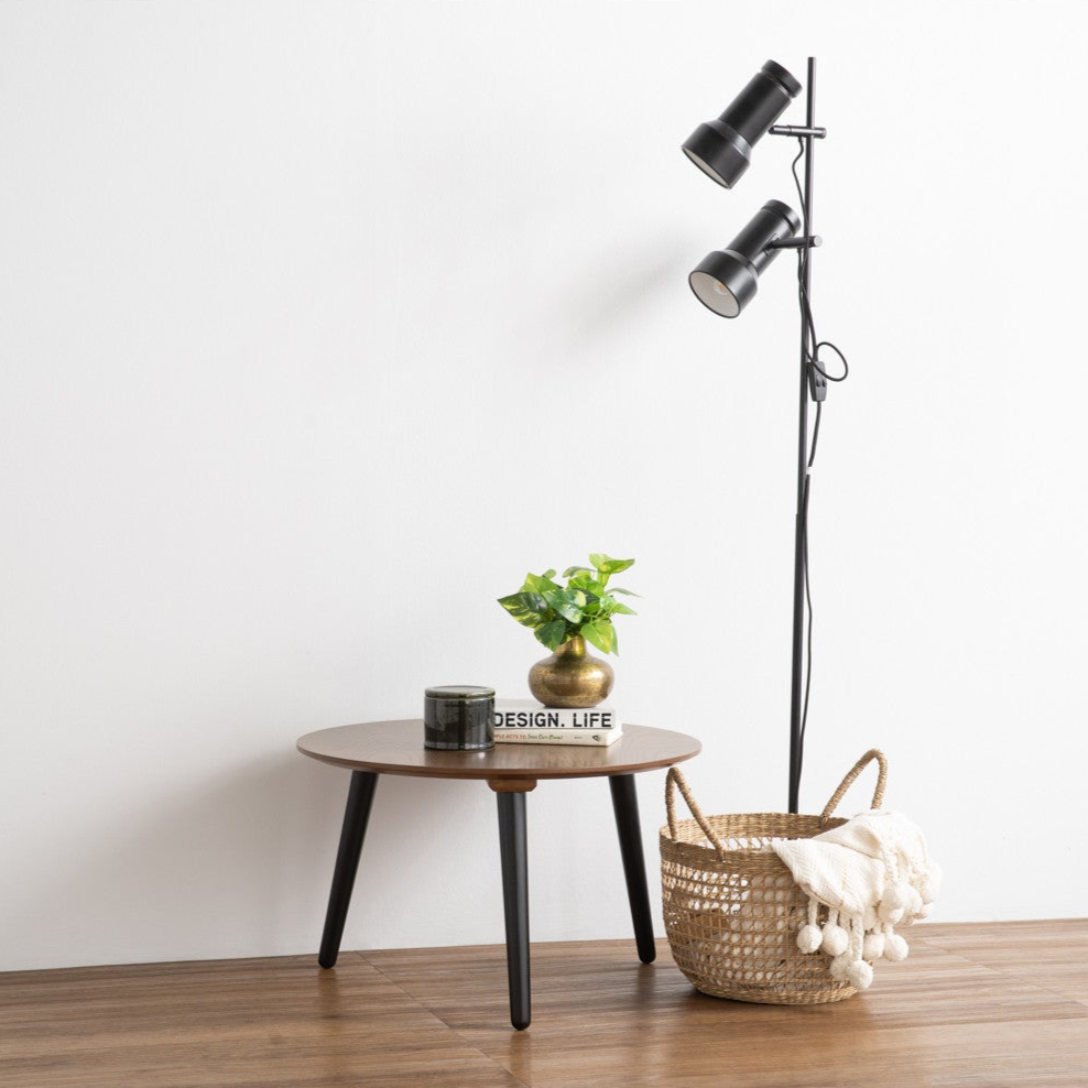 Modern floor lamp with a side table and decorative items on a wooden floor against a white wall.