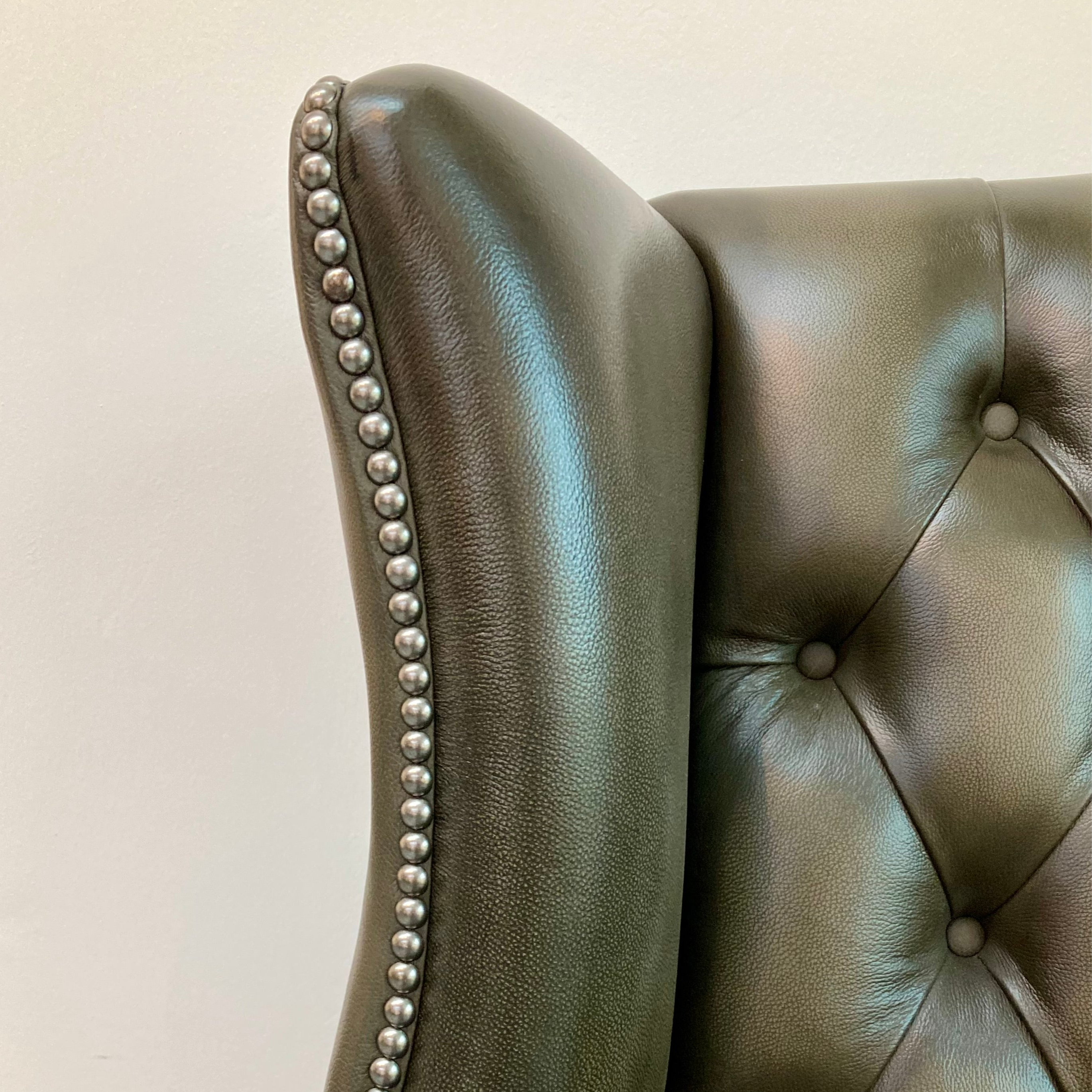 Close-up of a green leather headboard with studded details.